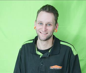 Male employee with brunette hair in front of green background