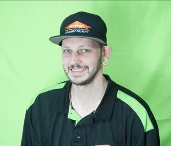 Male employee with brunette hair in front of green background