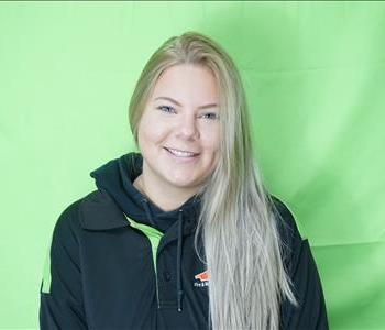 Female employee with blonde hair in front of green background