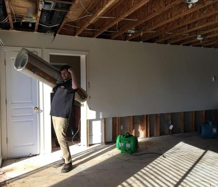Flood cut room with Servpro employee removing rolled carpet